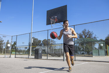 Junger männlicher Basketballspieler, der mit dem Ball auf dem Basketballplatz läuft - ISF13290