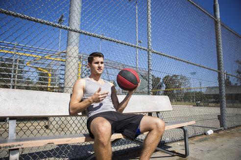 Junger männlicher Basketballspieler macht eine Pause auf der Bank - ISF13292