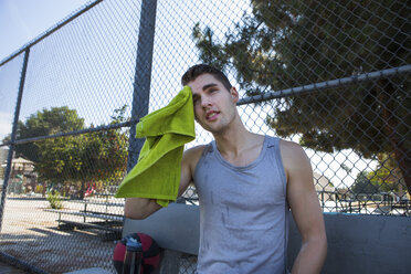 Young male basketball player wiping brow with towel - ISF13293