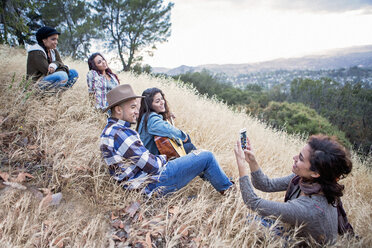 Junge Frau fotografiert ihre vier erwachsenen Geschwister auf einem grasbewachsenen Hügel - ISF13323