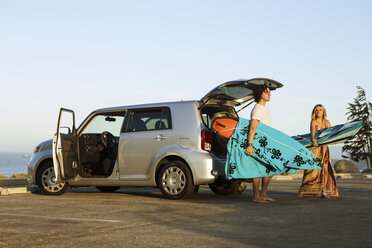 Pärchen nimmt Surfbretter aus dem Kofferraum eines Autos - ISF13348