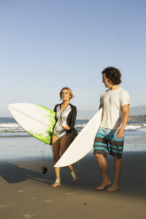 Couple walking on beach, carrying surfboards - ISF13350