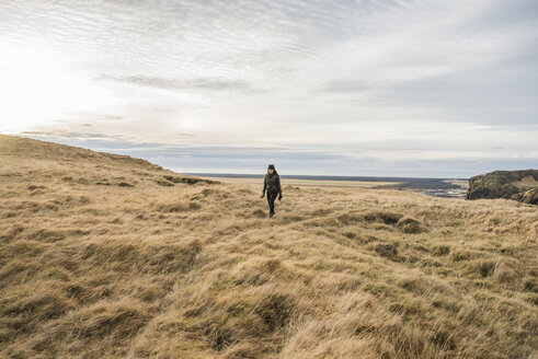 Female tourist walking across moorland, Skogafoss, Iceland - ISF13433