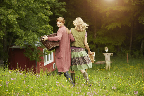 Zwei Frauen auf einem Feld, die einen Korb tragen - ISF13620