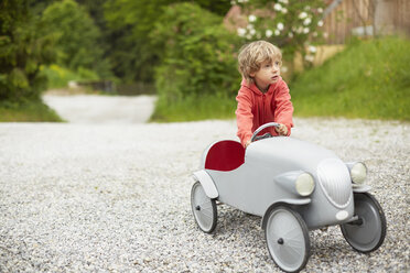 Junge spielt mit Oldtimer-Spielzeugauto im Freien, schaut weg - ISF13626