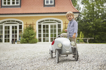 Junge spielt mit einem alten Spielzeugauto vor einem Haus - ISF13628