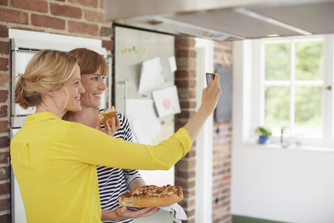 Frauen nehmen Selfie in der Küche mit Kuchen, lizenzfreies Stockfoto