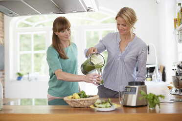 Women drinking green vegan smoothie in kitchen - ISF13650