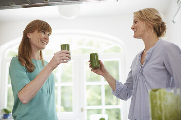 Frauen trinken grünen veganen Smoothie in der Küche - ISF13651