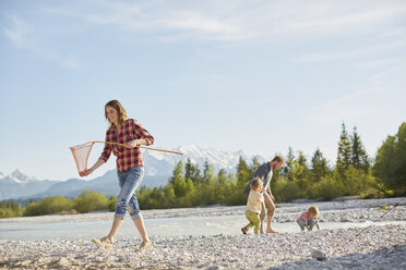 Young woman carrying fishing net by river, people in the background, Wallgau, Bavaria, Germany - ISF13668