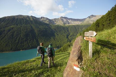 Rückansicht eines jungen Paares beim Wandern am Vernagt-Stausee, Schnalstal, Südtirol, Italien, lizenzfreies Stockfoto