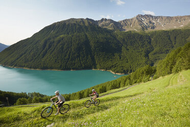 Young couple mountain biking at Vernagt reservoir, Val Senales, South Tyrol, Italy - ISF13681