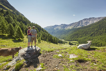 Rückansicht eines jungen Paares, das auf einem Felsblock steht und auf die Berge blickt, Schnalstal, Südtirol, Italien - ISF13683