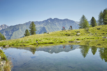 Junges Paar fährt mit dem Mountainbike den Berg hinunter, Karthaus, Schnalstal, Südtirol, Italien - ISF13697
