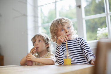 Two young brothers sitting at table drinking drinks with straws - ISF13701