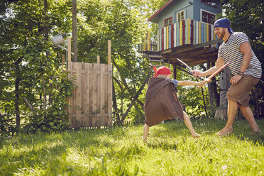 Vater und Sohn im Garten, in Kostümen, spielen mit vorgetäuschten Schwertern - ISF13718