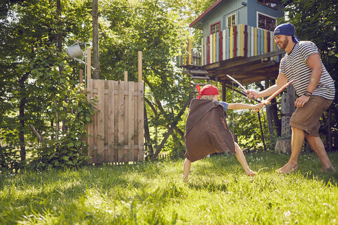 Vater und Sohn im Garten, in Kostümen, spielen mit vorgetäuschten Schwertern - ISF13718