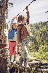 Two children walking across single rope bridge - ISF13754