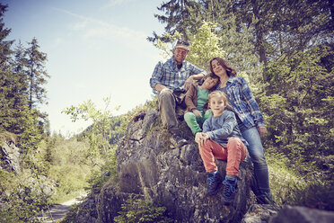 Porträt einer Familie auf einem Felsen im Wald sitzend - ISF13756