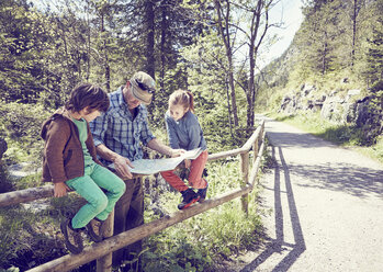 Father and children in forest, looking at map - ISF13757