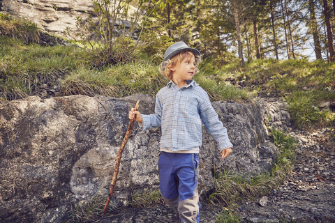 Ein Junge, der einen Stock hält, erkundet den Wald, lizenzfreies Stockfoto