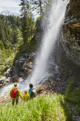 Junge Familie im Wald, stehend, beobachtet Wasserfall, Rückansicht - ISF13779