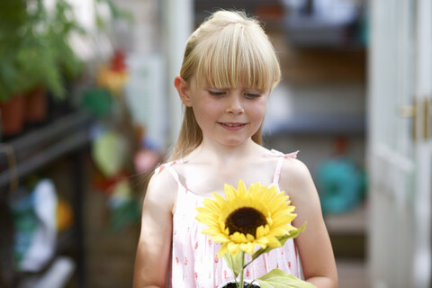 Porträt eines Mädchens mit Sonnenblume im Gewächshaus, lizenzfreies Stockfoto