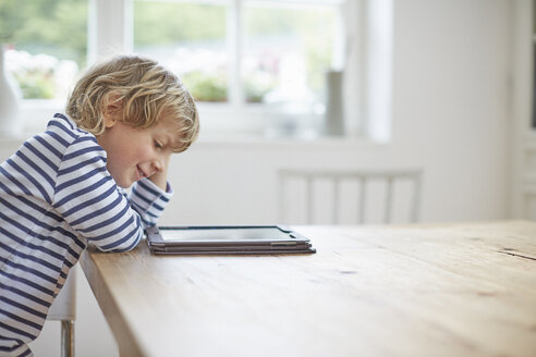 Seitenansicht eines Jungen, der am Tisch sitzt und ein digitales Tablet benutzt - ISF13803