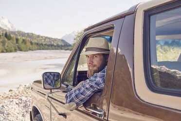 Mid adult man sitting in truck, leaning out window, looking at camera - ISF13823