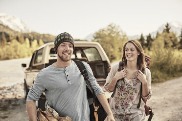 Young couple preparing to go hiking, carrying firewood, smiling - ISF13829