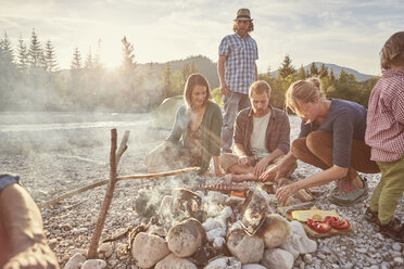 Family sitting around campfire preparing food - ISF13844