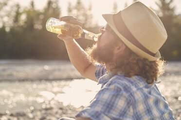 Seitenansicht eines mittleren erwachsenen Mannes mit Hut, der Bier aus einer Bierflasche trinkt - ISF13849