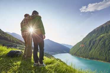 Junges Paar mit Blick auf den Vernagt-Stausee und das Bauernhaus Finailhof, Schnalstal, Südtirol, Italien - ISF13926