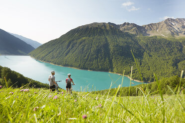 Junges Paar auf Mountainbikes mit Blick auf den Vernagt-Stausee, Schnalstal, Südtirol, Italien - ISF13927