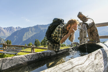 Junger männlicher Wanderer wäscht sein Gesicht in einem rustikalen Trog, Karthaus, Schnalstal, Südtirol, Italien - ISF13934