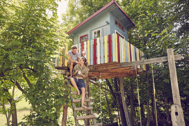 Junges Paar sitzt auf der Leiter eines Baumhauses - ISF13942