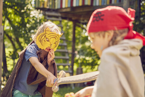 Zwei junge Brüder im Garten, die Kostüme tragen und mit vorgetäuschten Schwertern spielen - ISF13944