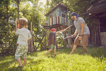 Vater und zwei Söhne im Garten, in Kostümen, spielen mit vorgetäuschten Schwertern - ISF13945