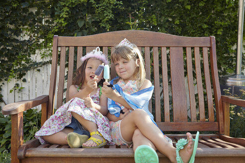 Mädchen genießen einen Eislutscher auf einer Gartenbank - ISF14008