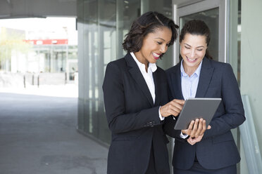 Zwei Geschäftsfrauen, die ein digitales Tablet betrachten, im Freien - ISF14022