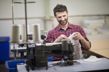 Männlicher Textildesigner an einer Nähmaschine in einer alten Textilfabrik - ISF14074