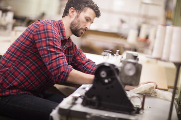 Male weaver using sewing machine in old textile mill - ISF14075