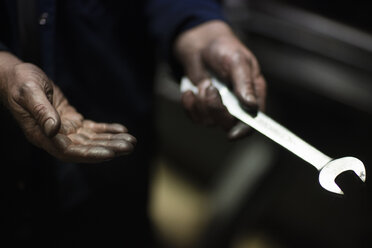 Ölige Hände eines männlichen Webers, der eine alte Webmaschine in einer Textilfabrik repariert - ISF14077