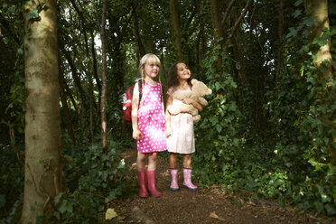 Zwei Mädchen tragen Teddybär und Rucksack im Wald - ISF14108