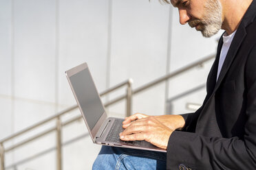 Geschäftsmann sitzt im Freien und benutzt einen Laptop - AFVF00631