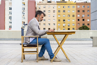 Geschäftsmann sitzt auf der Dachterrasse und arbeitet am Laptop - AFVF00644