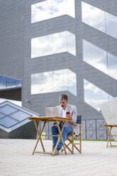Spanien, Barcelona, Geschäftsmann bei der Arbeit an einem Laptop im Freien - AFVF00645