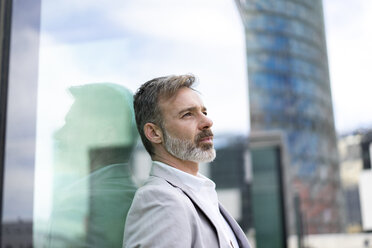 Spain, Barcelona, pensive businessman leaning against glass facade - AFVF00648