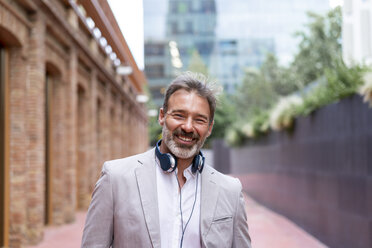 Portrait of laughing businessman with headphones - AFVF00658