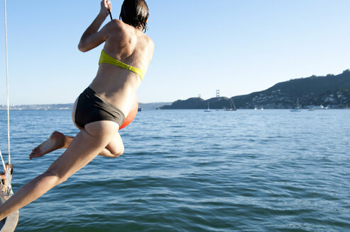 Junge Frau schwingt an einem Bootstau, Sausalito, Kalifornien, USA - CUF33259